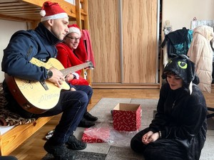 Policjant gra na gitarze w towarzystwie Mikołaja