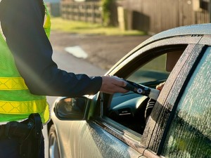 Kierujący dmucha w urządzenie, które trzyma w ręce policjant