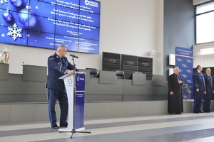 Komendant przemawia do mikrofonu w auli wśród zaproszonych gości