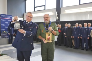 Komendant i harcerz pozują do zdjęcia z symbolicznym światełkiem