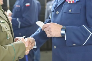 Ręka policjanta i strażnika granicznego trzyma opłatek