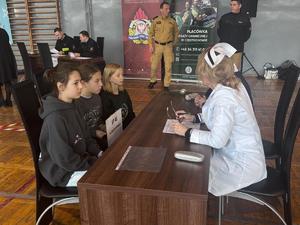 Uczniowie przy stoliku rozmawiają z pielęgniarkami podczas jednej z  konkurencji