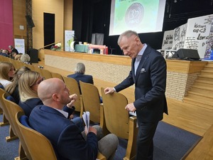 Mężczyzna rozmawia z uczestnikiem, który siedzi na widowni