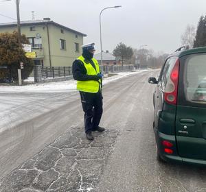 Policjant stoi przy pojeździe, który zatrzymał do kontroli