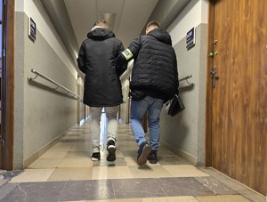 Policjant doprowadza zatrzymanego korytarzem