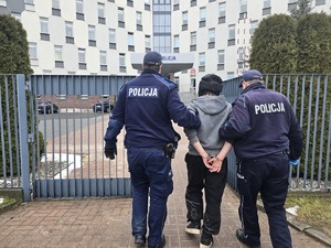 Policjanci doprowadzają zatrzymanego