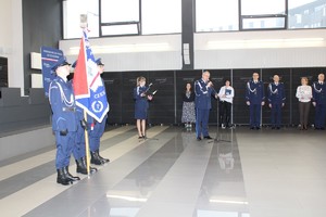 Komendant przemawia do mikrofonu, obok stoi delegacja ze sztandarem