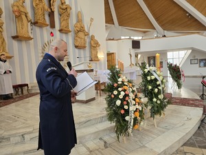 Policjant podczas ceremonii przemawia do mikrofonu