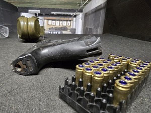 Magazynek, naboje, broń i okulary i słuchawki leżą na stoliku