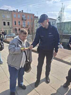 Policjant wręcza opaskę odblaskowa dziecku