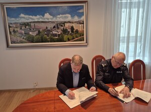 Komendant i rektor siedzą przy stoliku i podpisują dokumenty