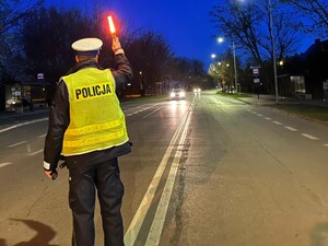 Policjant na drodze unosi latarkę do gory