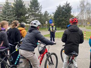 Policjant rozmawia z uczestnikami turnieju, którzy z rowerami znajdują się na podwórku