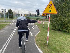 Uczestnik turnieju jadąc na rowerze, wyciąga prawą rękę w bok
