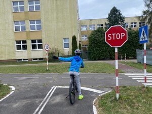 Uczestnik turnieju dojeżdża rowerem do skrzyżowania i wyciąga lewą rękę w bok