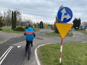 Uczestnik turnieju na rowerze dojeżdża do skrzyżowania i wyciąga prawą rękę w bok