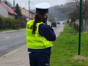 Policjantka stoi przy drodze i kontroluje ruch pojazdów