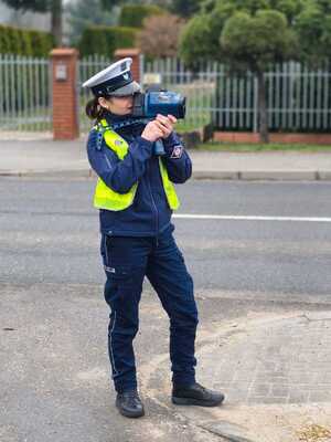 Policjantka przy drodze mierzy prędkość urządzeniem do pomiaru