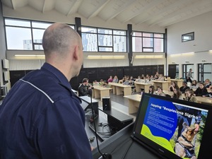 Policjant przy wyświetlaczu monitoru mówi do u8czestników konferencji