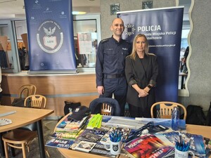 Policjant i kobieta pozują do zdjęcia przy policyjnym stoisku