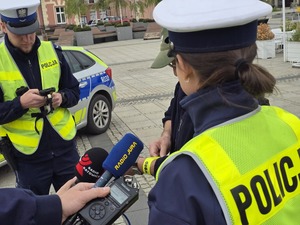 Policjanci rozmawiają z mężczyzną, który zakłada opaskę odblaskową na rękę
