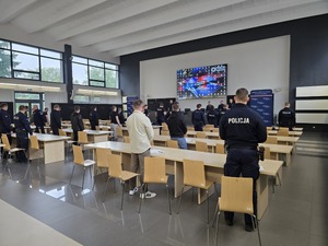 Policjanci, którzy biorą udział w konkursie stoją w auli przy swoich miejscach