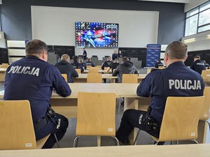 Policjanci podczas konkursu siedzą w ławkach w auli komendy