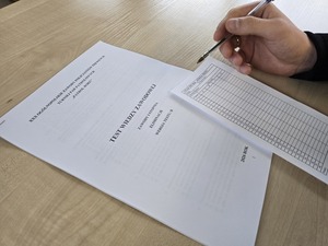 Długopis trzymany w dłoni nad testem z kartą odpowiedzi