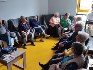Seniorzy siedzą w sali podczas debaty