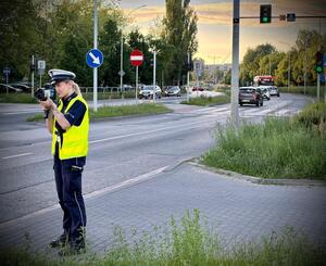 Policjantka przy drodze mierzy prędkość urządzeniem