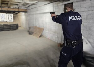 Policjant strzela z pistoletu do tarczy