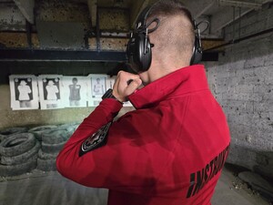 Instruktor stoi na strzelnicy skierowany w stronę tarczy