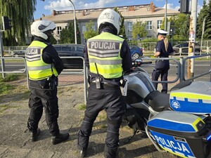 Policjanci stoja przy motocyklach w okolicy przejścia dla pieszych