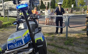 Policyjny motocykl w rejonie przejścia dla pieszych przy którym stoi policjantka