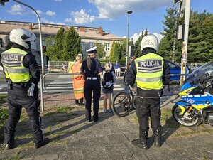 Policjanci w rejonie przejścia dla pieszych rozmawiają z pieszymi uczniami